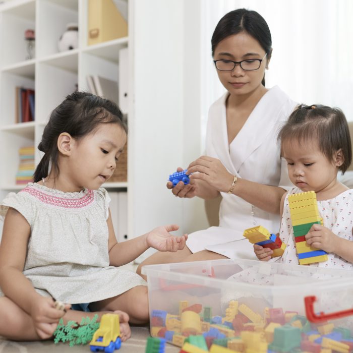 Nurse playing and two little girls playing with plastic cubes